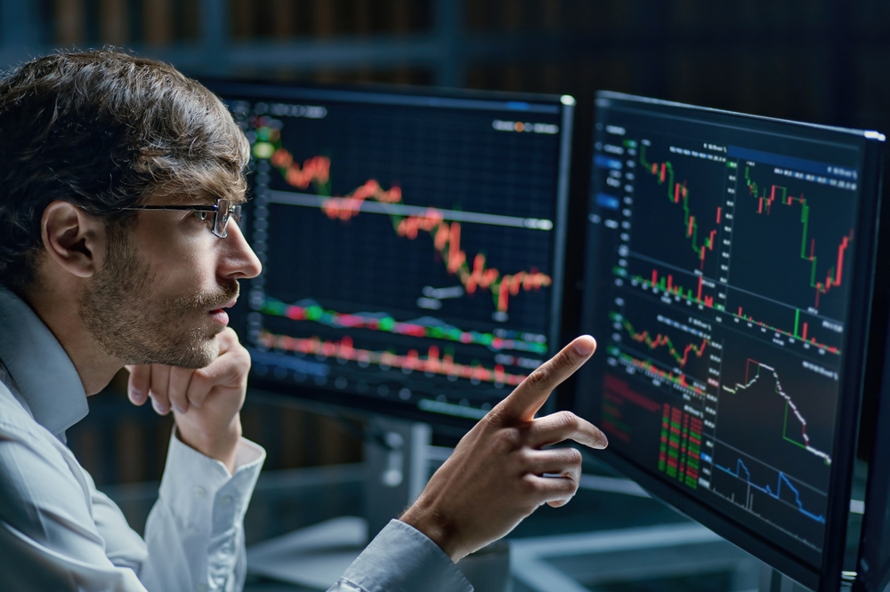 BusinessmanComparingStockMarketDataLateInTheEvening | Latino Inversores - Inversión y Trading En Línea